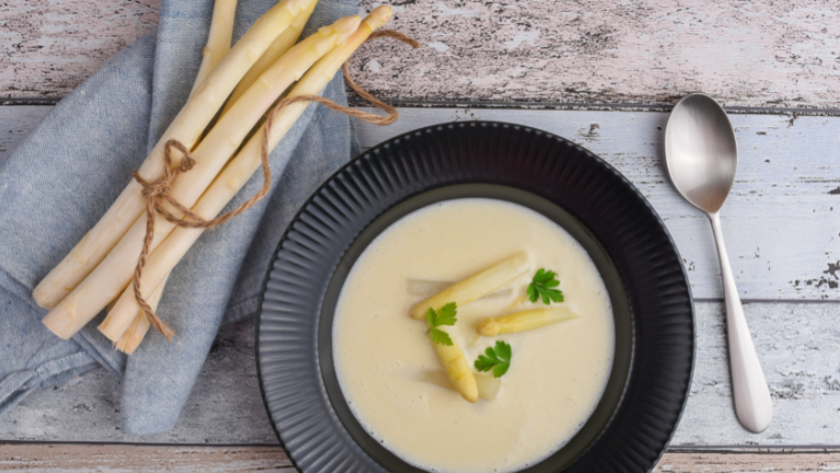 Bundeltje witte asperges en een soepbord met aspergesoep