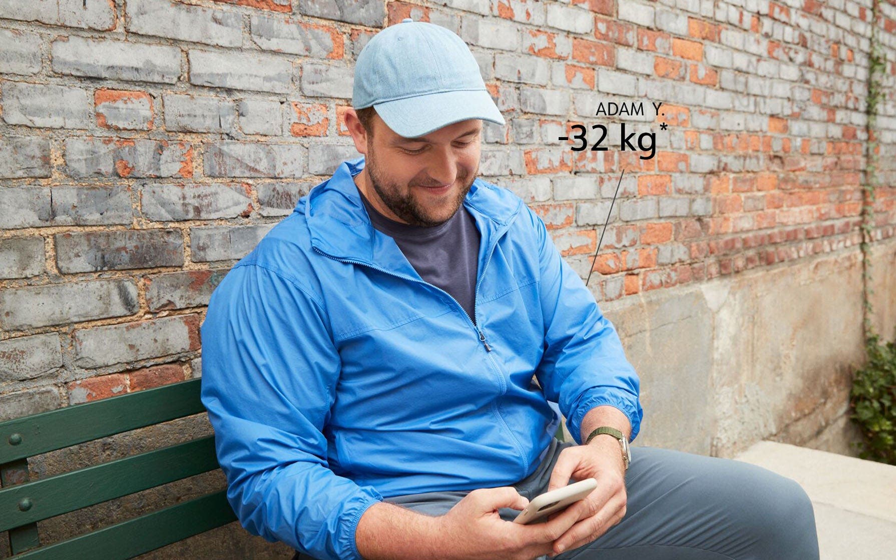 WW Member Adam Y. sitting on a bench, looking at his phone.