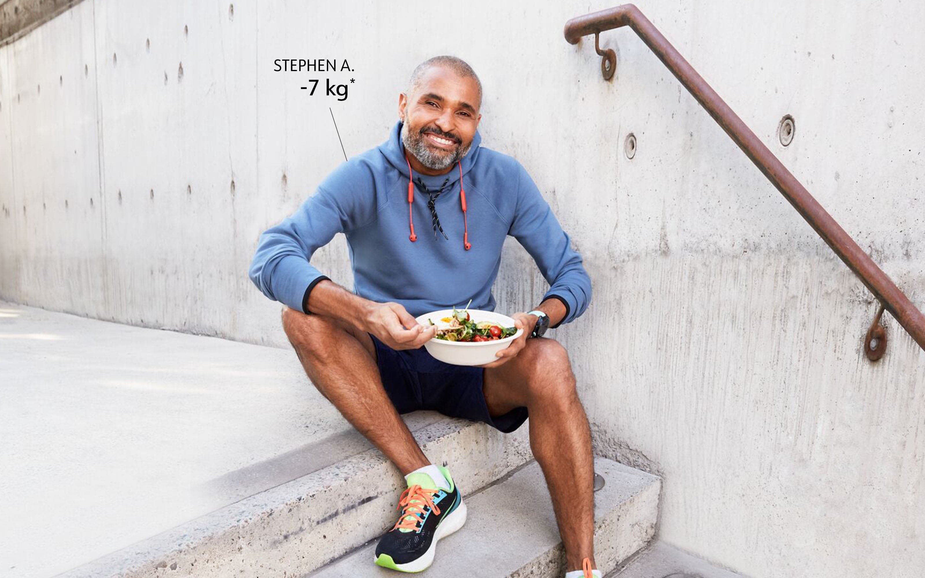 WW Member Stephen, sitting on stairs and eating a salad.