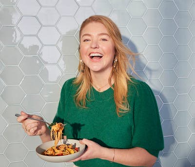 Woman eating a bowl of pasta.