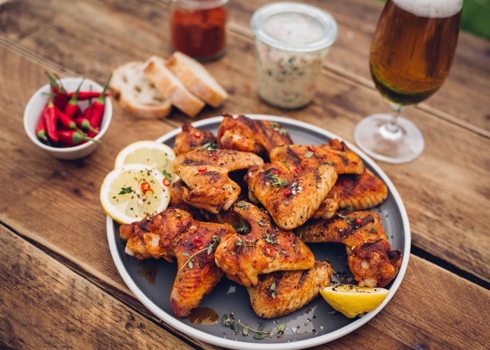 Spicy chicken wings on a picnic table with beer