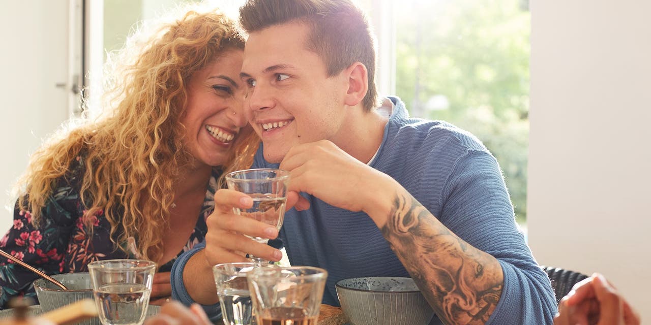 Un couple est assis à table, l'homme savoure un verre de vin.