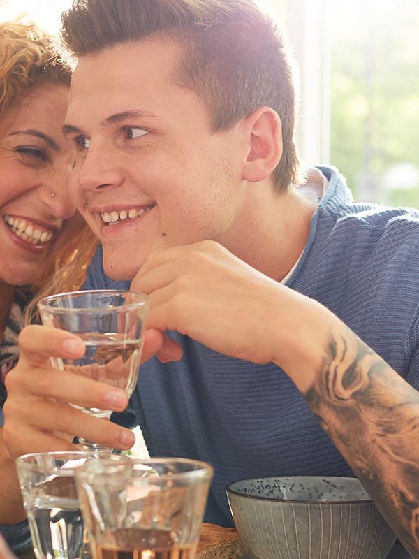 Un couple est assis à table, l'homme savoure un verre de vin.