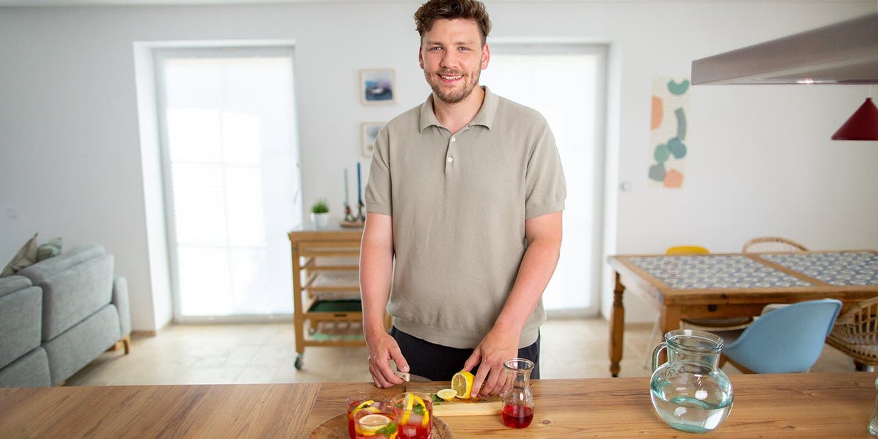 Un homme avec des cheveux courts prépare une boisson dans la cuisine