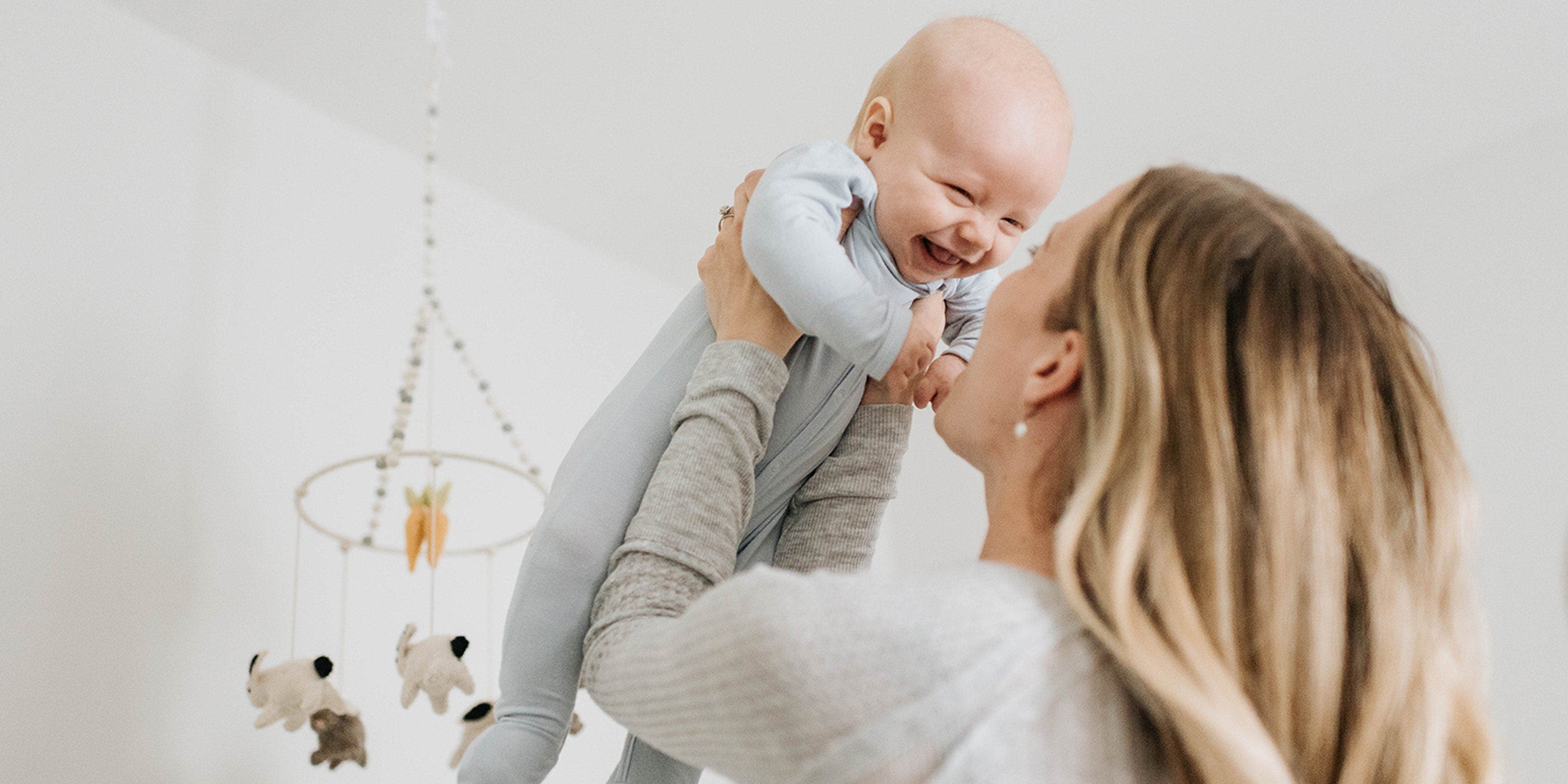 Une femme soulève son bébé qui sourit.