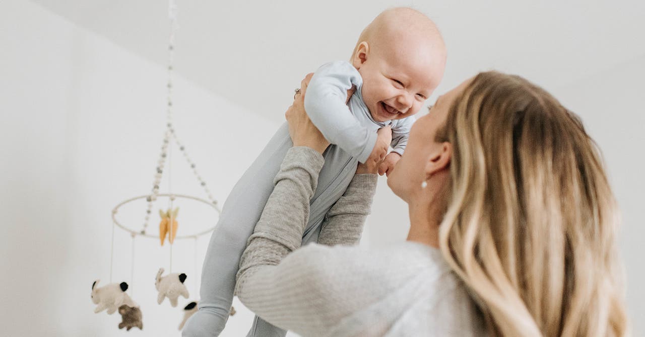 Une femme soulève son bébé qui sourit.
