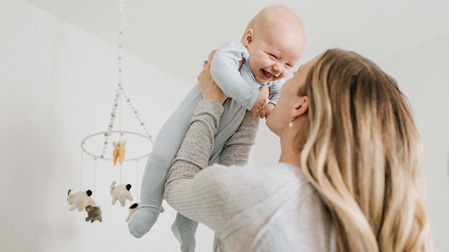 Une femme soulève son bébé qui sourit.