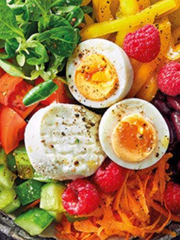 Eine Bowl mit frischem Gemüse, Huelsenfruechten, Käse und Ei