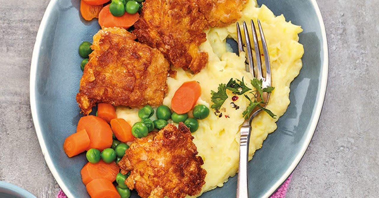 Une assiette avec des nuggets de poisson, de la purée de pommes de terre et des légumes mélangés