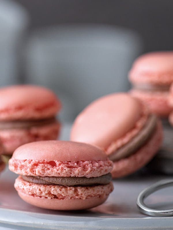 Auf einem Teller liegen rosa Macarons gefüllt mit einer Schokocreme