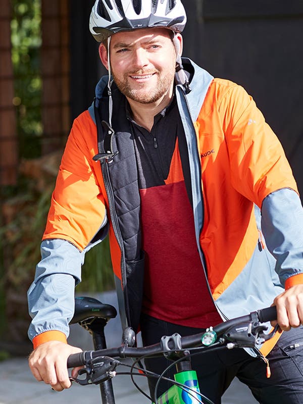 Ein Mann in Sportkleidung steht neben seinem Velo