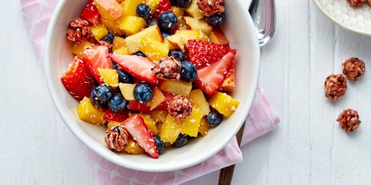 Eine Schüssel Fruchtsalat mit Mango, Erdbeeren, Heidelbeeren und Müsli