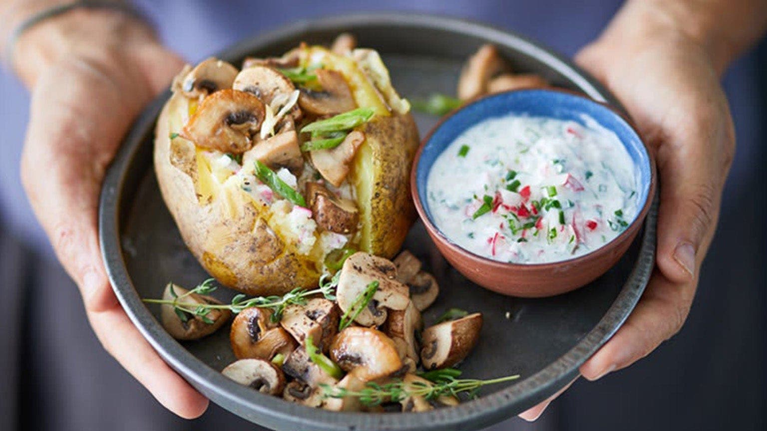 Pommes de terre farcies au four avec champignons et dip au skyr sur assiette noire