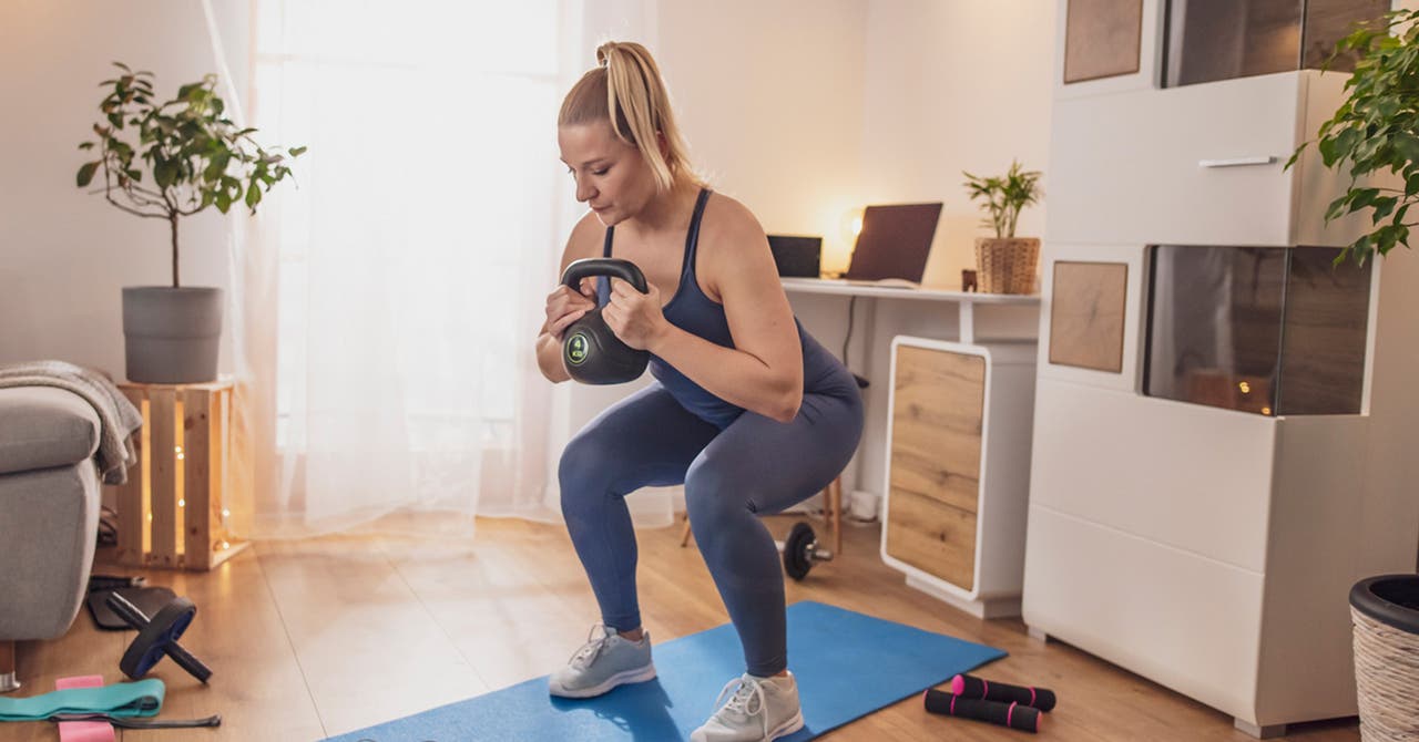 Junge Frau trainiert zuhause mit Kettleball