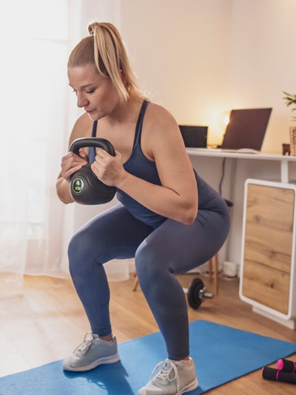 Junge Frau trainiert zuhause mit Kettleball
