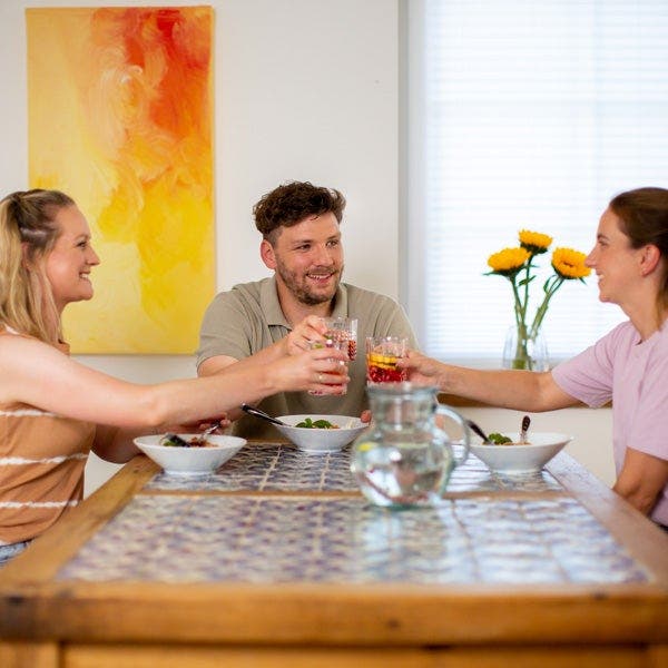 Nils stößt mit Freunden am Tisch an