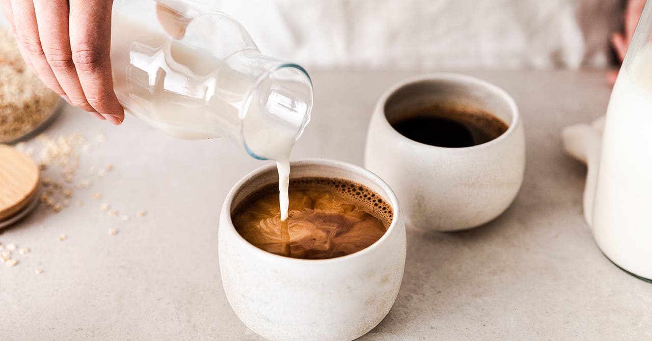 Zwei Tassen Kaffee, in die Milch gegossen wird