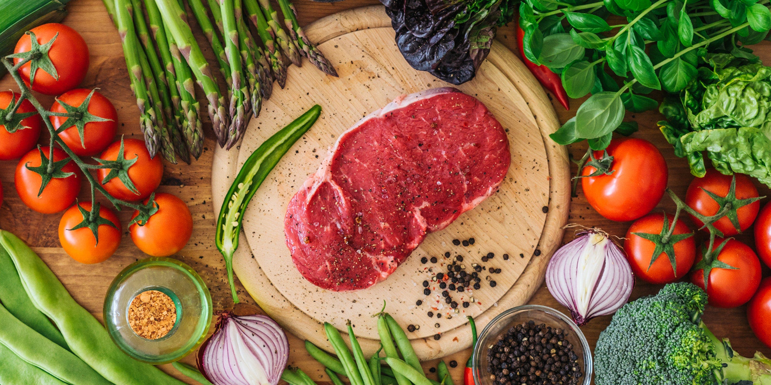 Une plaque sur laquelle se trouve un morceau de viande rouge, entouré de nombreux légumes.