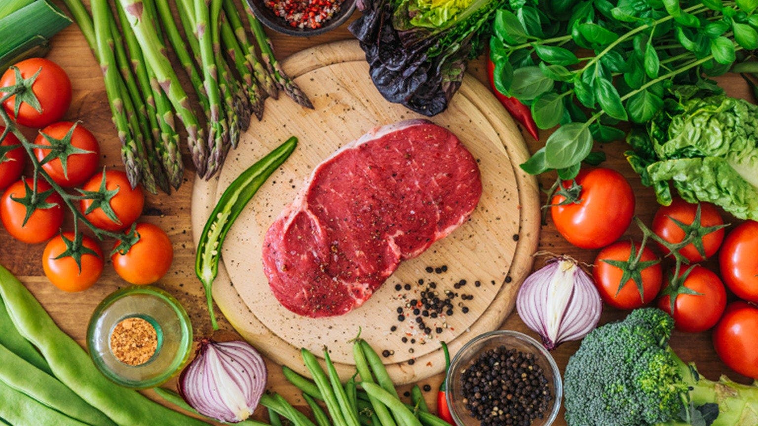 Une plaque sur laquelle se trouve un morceau de viande rouge, entouré de nombreux légumes.