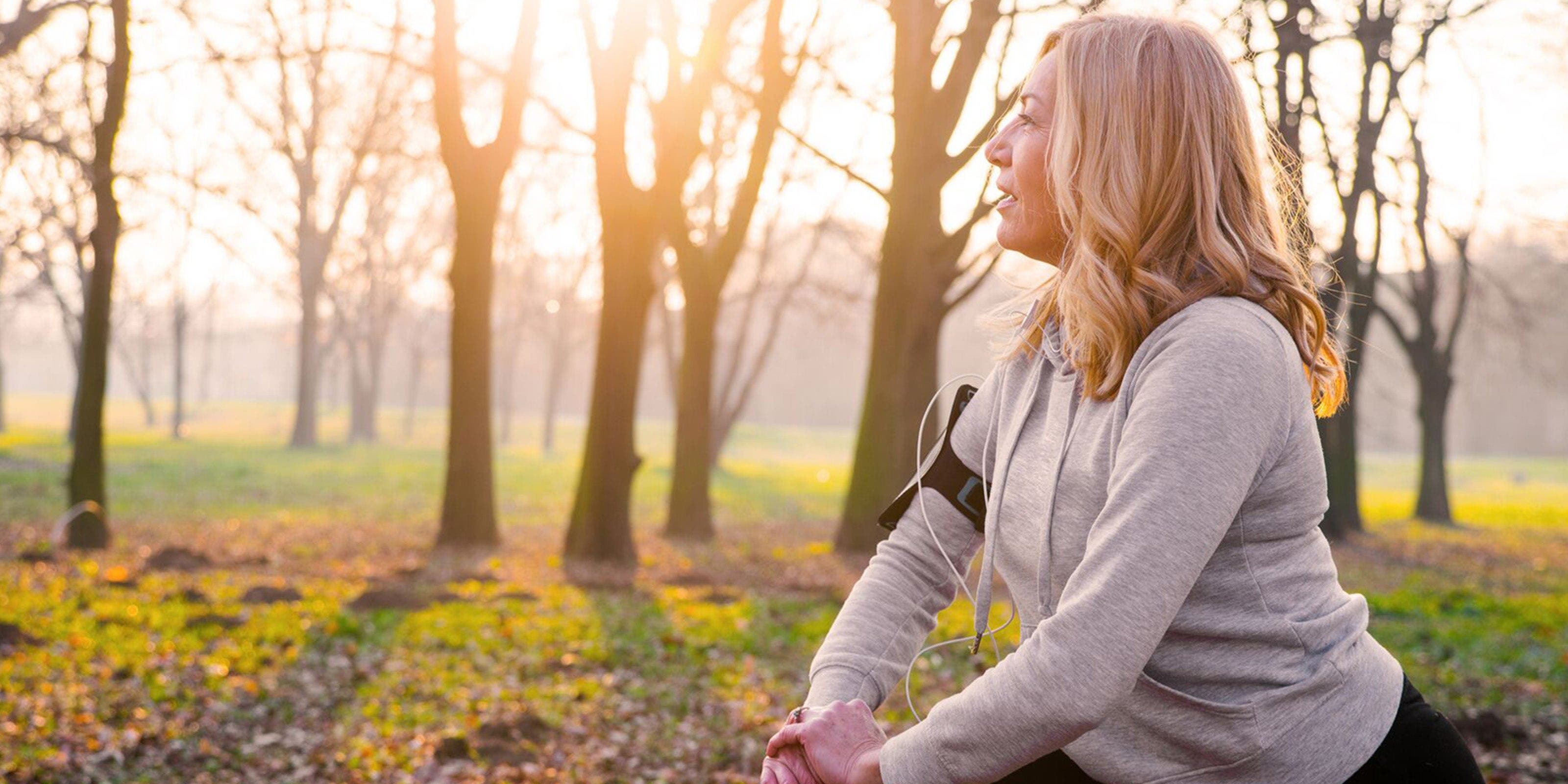 Blonde Frau in Sportkleidung stretcht sich im Wald