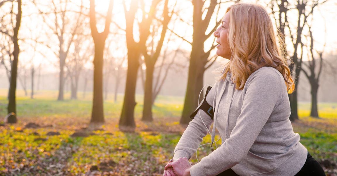 Blonde Frau in Sportkleidung stretcht sich im Wald