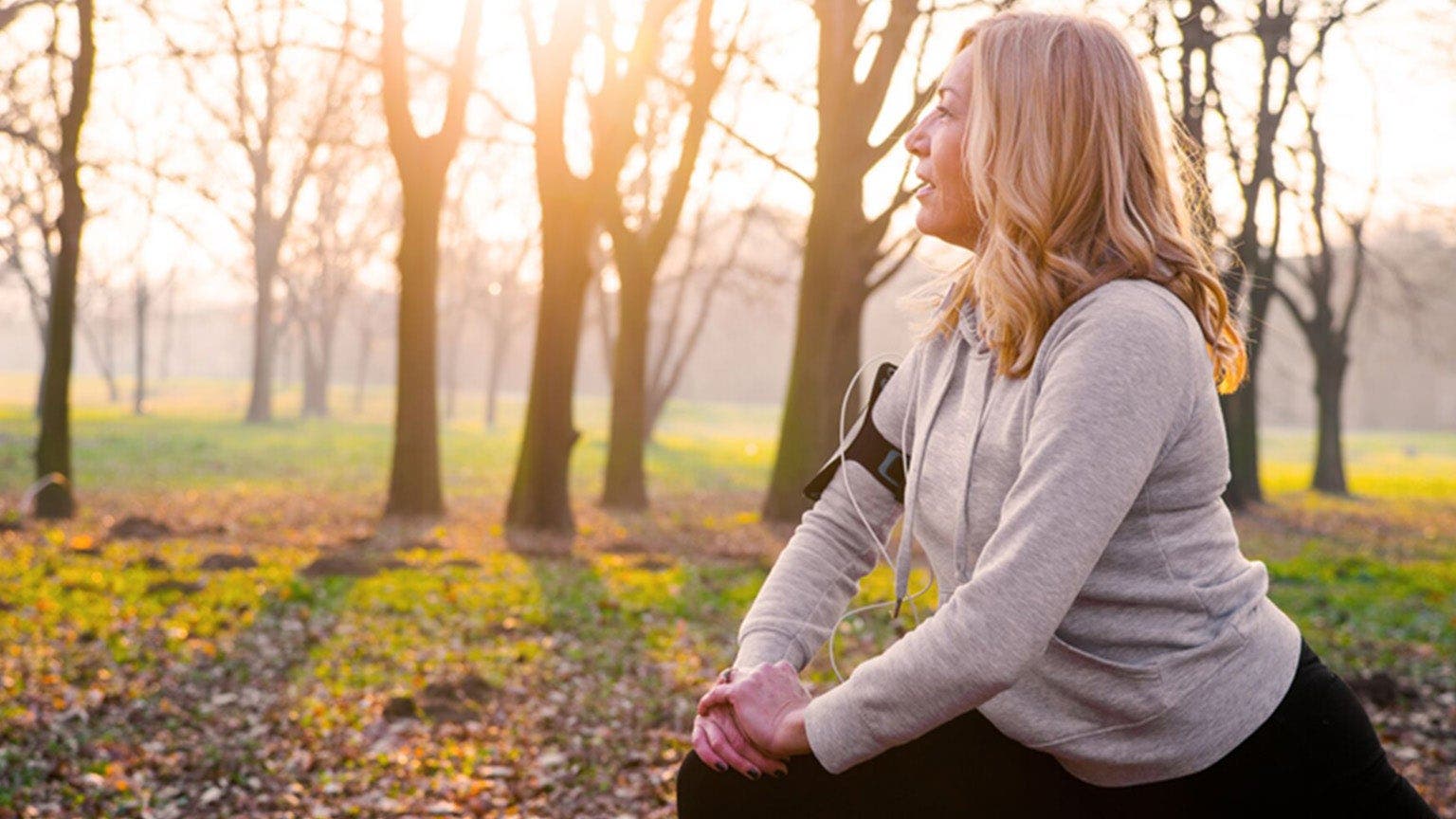 Blonde Frau in Sportkleidung stretcht sich im Wald