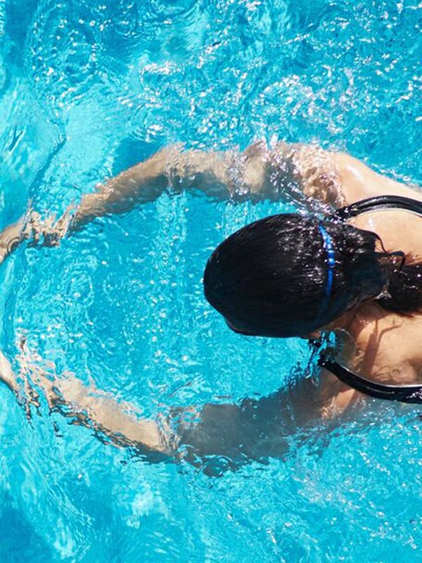 Frau in Badeanzug trainiert Brustschwimmen.