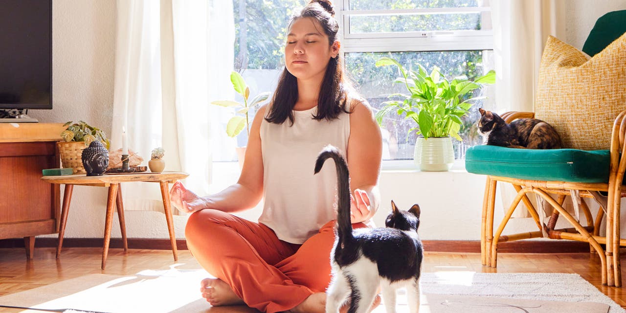 Une jeune femme assise en tailleur sur un tapis de yoga