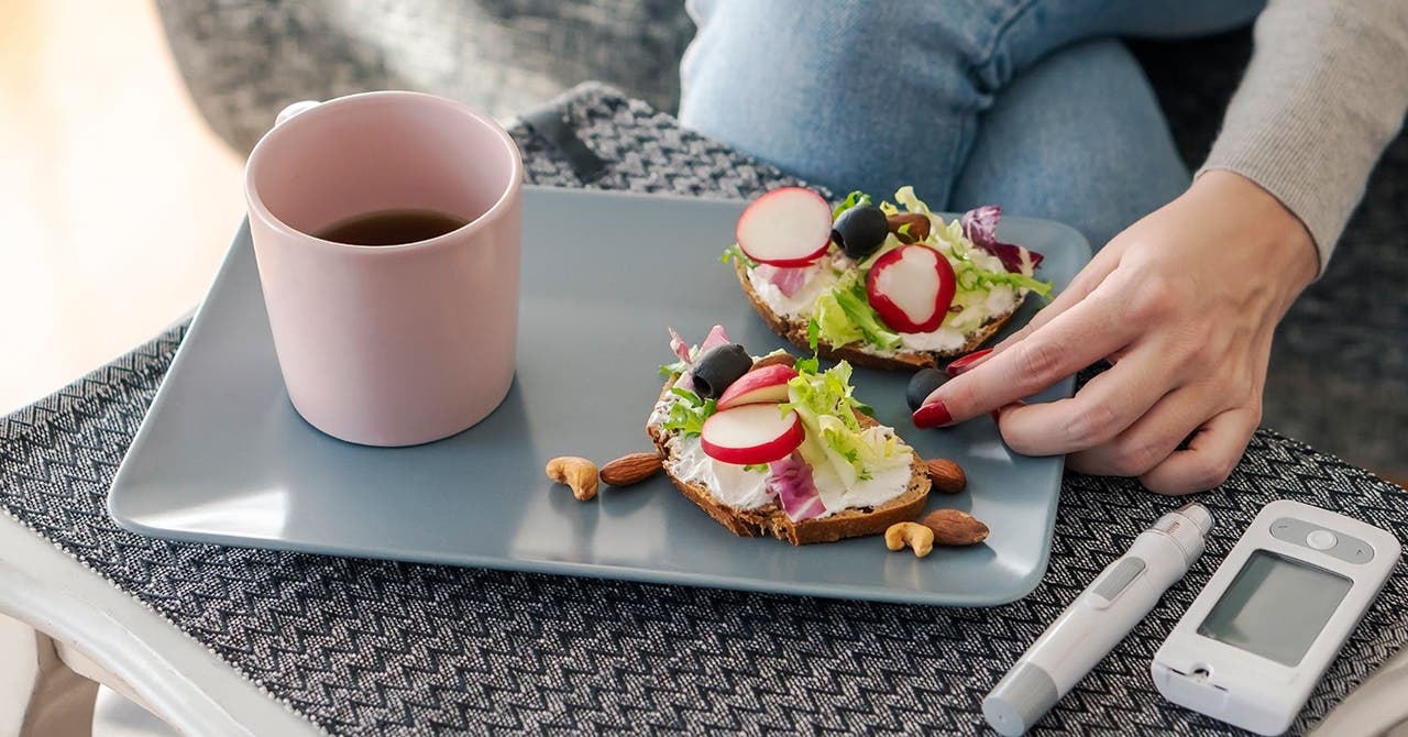 Ein Frühstücksteller mit belegtem Brot und Kaffee, daneben liegt das Blutzuckermessgerät.