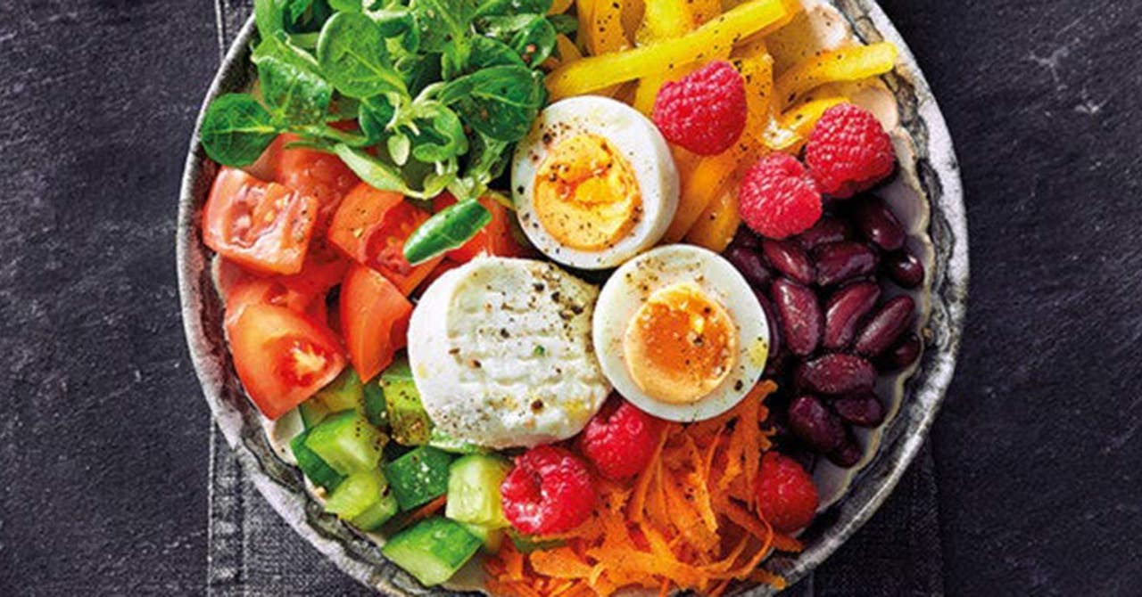 Eine Bowl mit frischem Gemüse, Huelsenfruechten, Käse und Ei