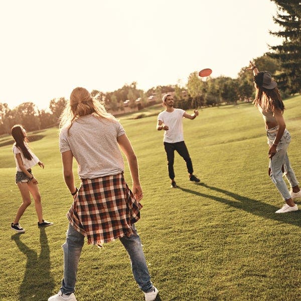 Junge Leute spielen draußen Frisbee