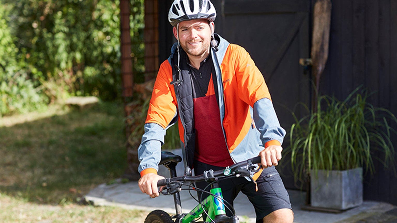 Ein Mann mit Fahrradhelm und Sportkleidung steht neben seinem Fahrrad