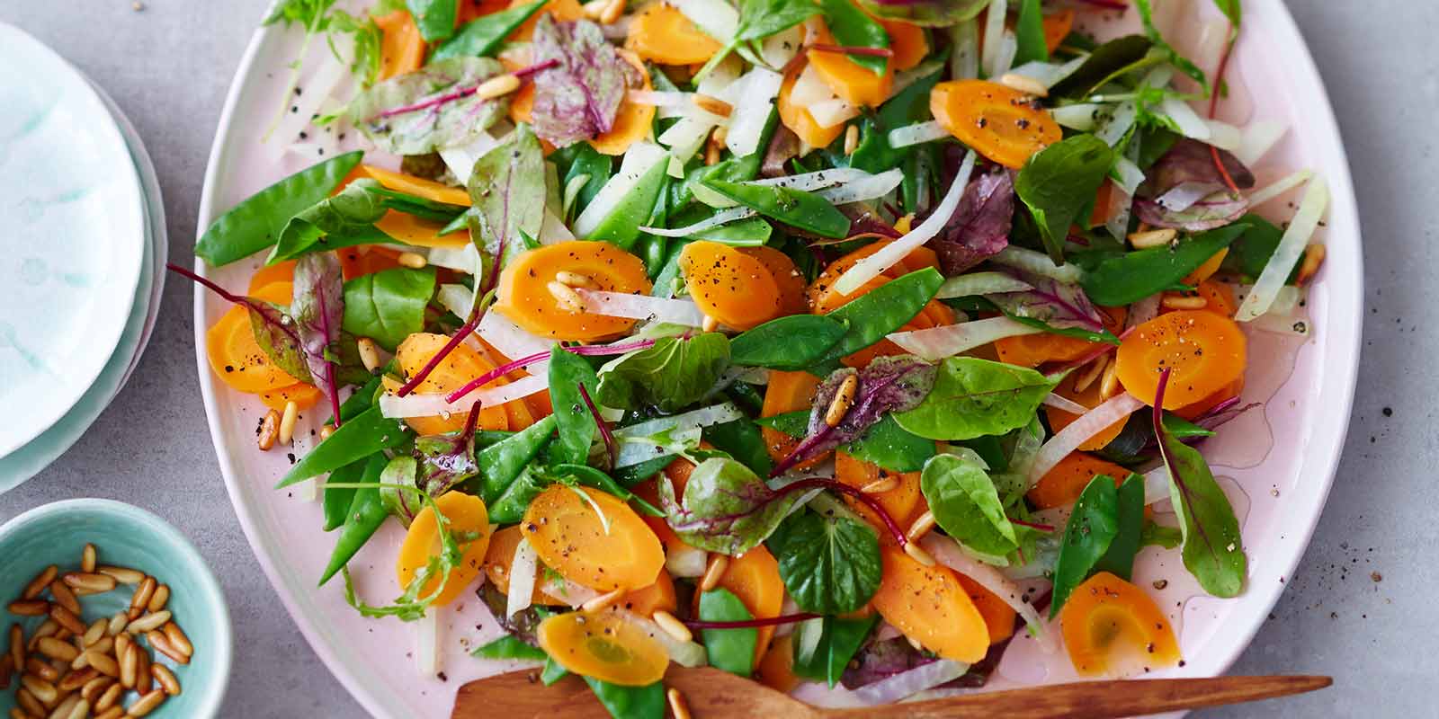 Ein Teller mit einem frischen Möhren-Kohlrabi-Salat mit Pinienkernen