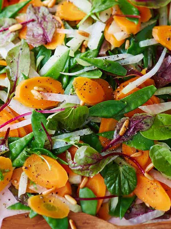Ein Teller mit einem frischen Möhren-Kohlrabi-Salat mit Pinienkernen