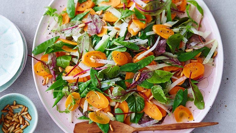 Ein Teller mit einem frischen Möhren-Kohlrabi-Salat mit Pinienkernen