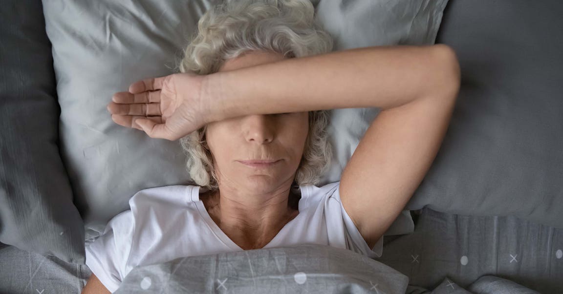 Frau liegt im Bett und verschränkt Arm über dem Gesicht
