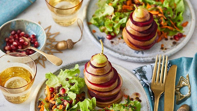 Rote-Bete-Birnen-Türmchen sind auf einer festliche gedeckten Tafel schön angerichtet.