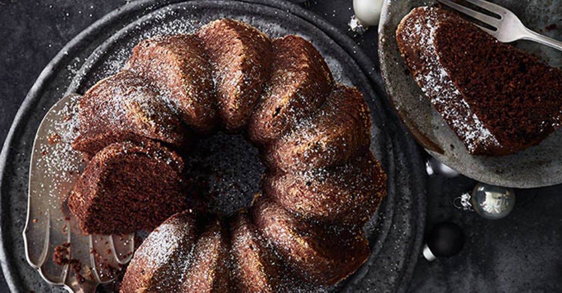 Gewürzkuchen-Gugelhupf auf Servierplatte und Weihnachtskugeln daneben
