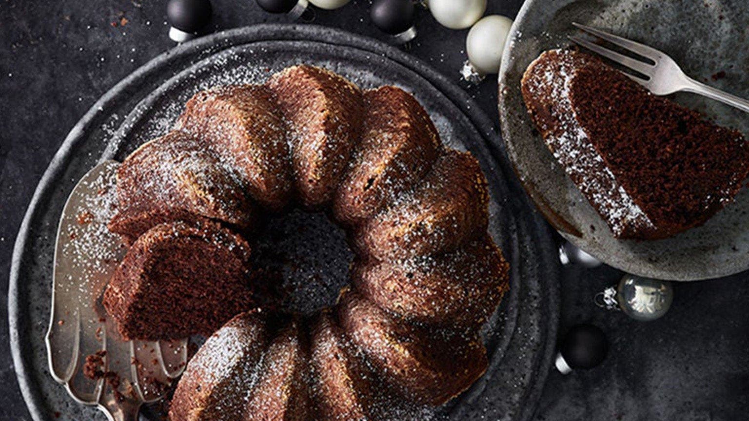 Gewürzkuchen-Gugelhupf auf Servierplatte und Weihnachtskugeln daneben