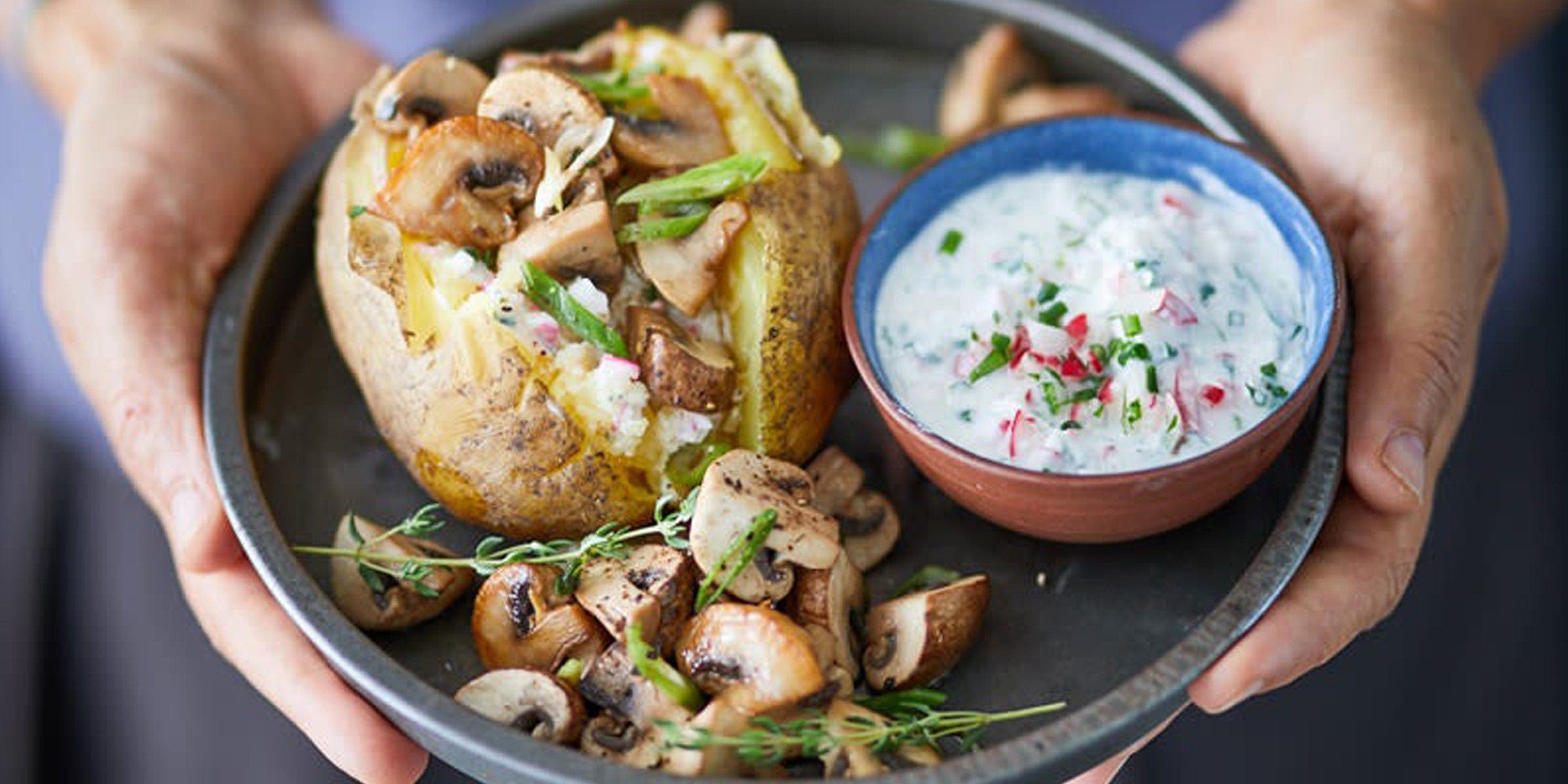 Gefüllte Ofenkartoffel mit Pilzen und Skyr Dip auf schwarzem Teller