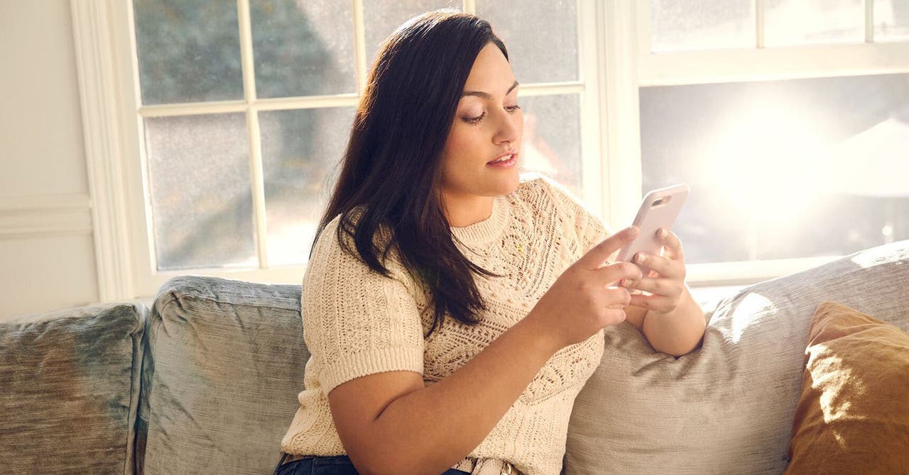 Frau sitzt auf Sofa und schaut aufs Handy