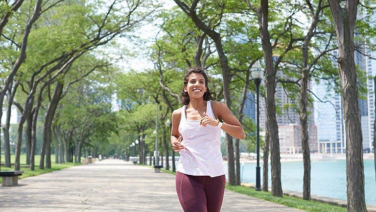 Junge Frau mit braunem Haar joggt im Park.