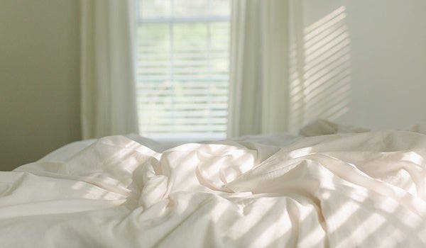 Bett in Schlafzimmer mit weißer Bettwäsche