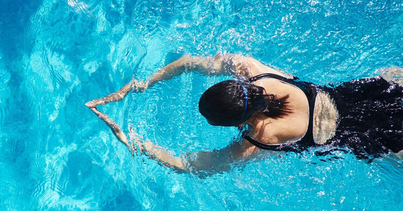 Frau in Badeanzug trainiert Brustschwimmen.