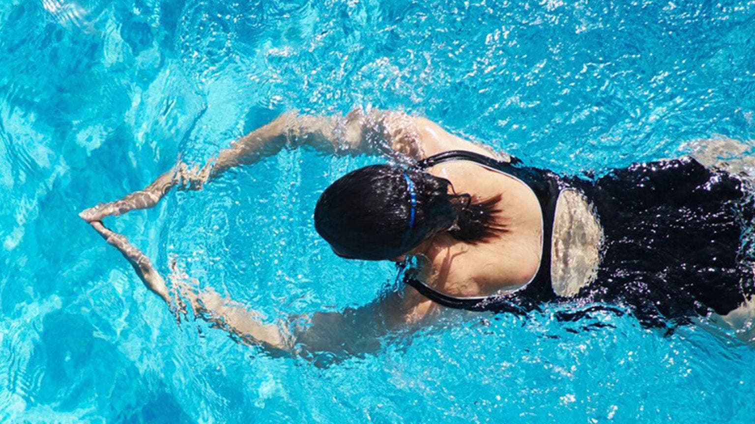 Frau in Badeanzug trainiert Brustschwimmen.