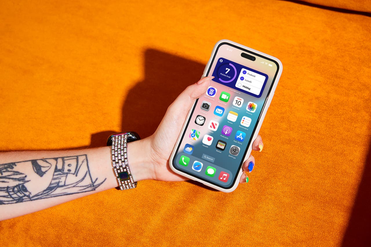 En person håller en iPhone som visar upp en blandning av teknik och personligt uttryck.
