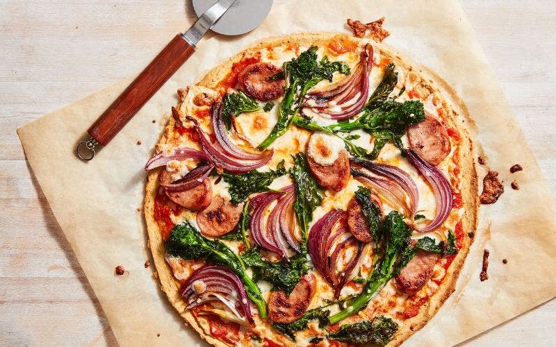 A pizza on a sheet of parchment paper.