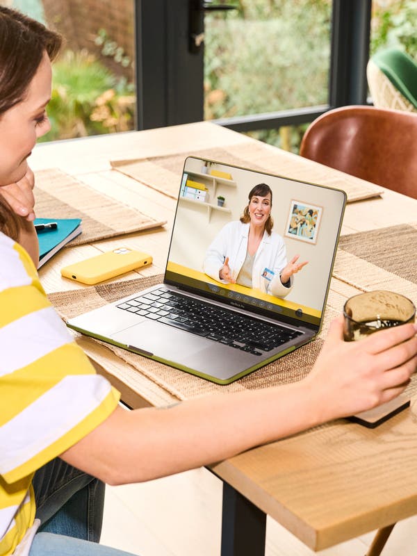 a woman sitting at a table with a laptop talking to the doctor