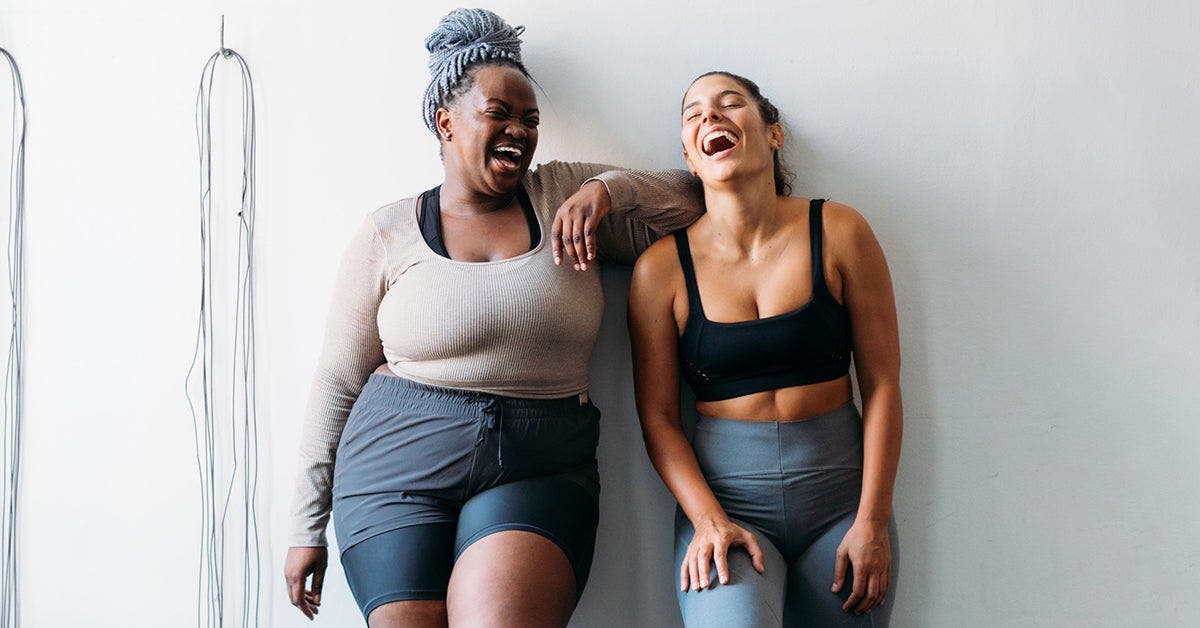  Two women laughing after a workout class. 