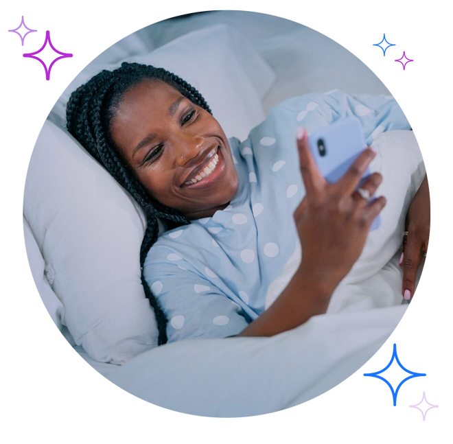 Woman in pajamas looking at phone while tucked in bed